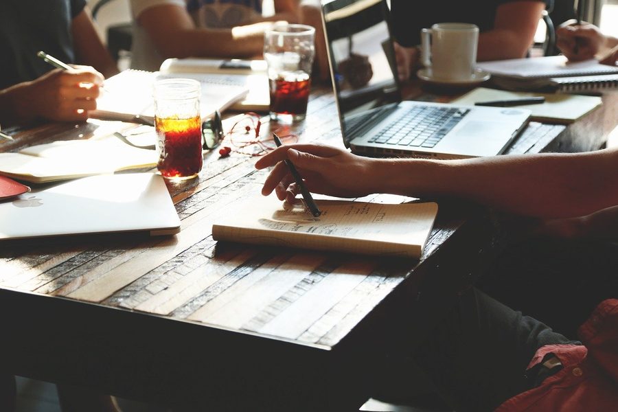 Réunion de préparation autour d'une table : carnet de notes, ordinateur et échanges sur le projet