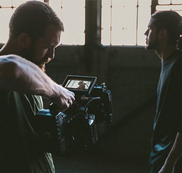 Vidéaste en plein tournage, caméra à l'épaule, filmant une personne dans un atelier